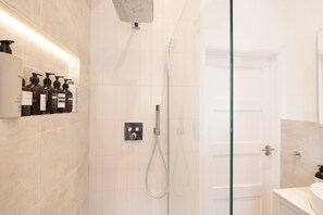 Enjoy a comfortable bathroom with a glass-enclosed shower, handheld showerhead, and convenient storage for toiletries.