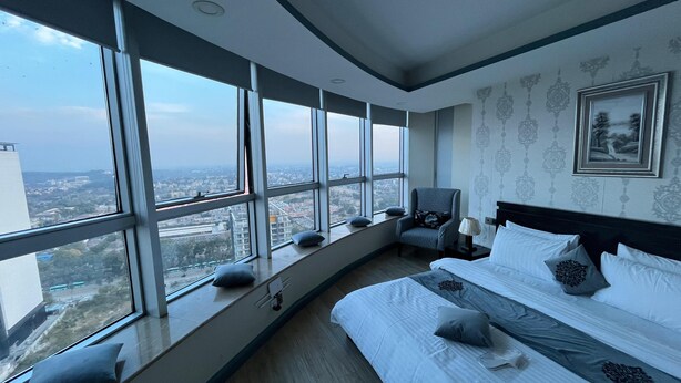 Un dormitorio moderno con una cama grande, una silla junto a la ventana y vistas a la ciudad.