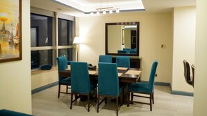 Un comedor con mesa y sillas, un espejo grande y un ventanal con vistas a la ciudad de noche.