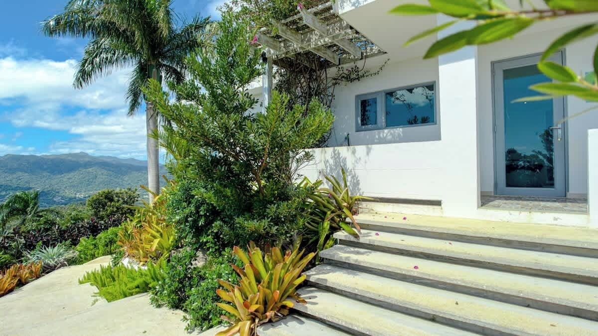 Uma casa moderna com fachada branca, uma varanda e vista para montanhas.