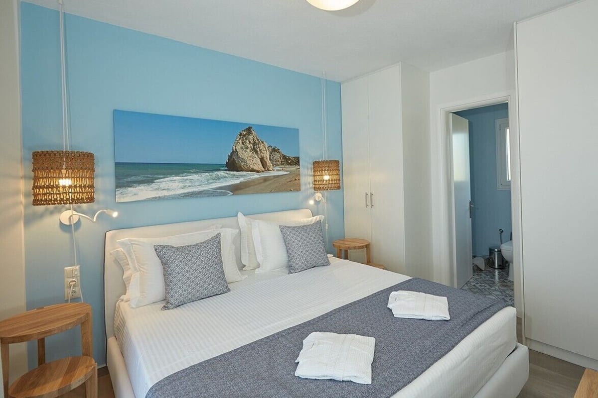 Une chambre à coucher avec un lit, deux lampes de chevet, un tableau représentant une plage et une armoire.