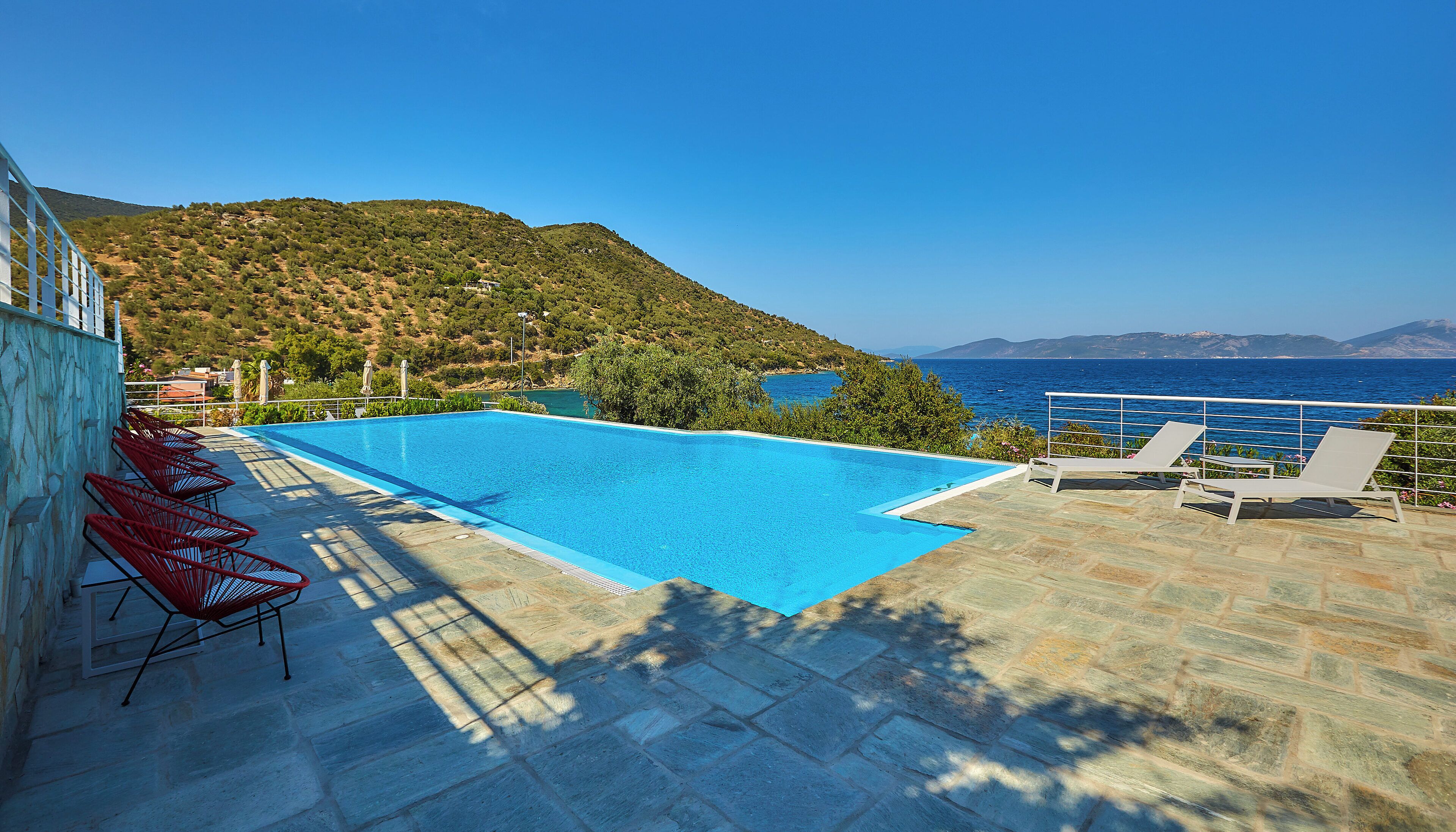 A swimming pool with a view of the sea and mountains.