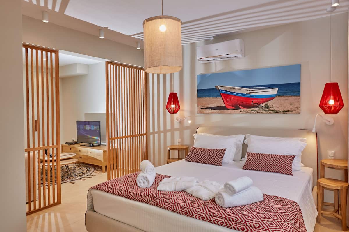 Une chambre d’hôtel avec un lit, un tableau représentant un bateau sur la plage et une cloison en bois.
