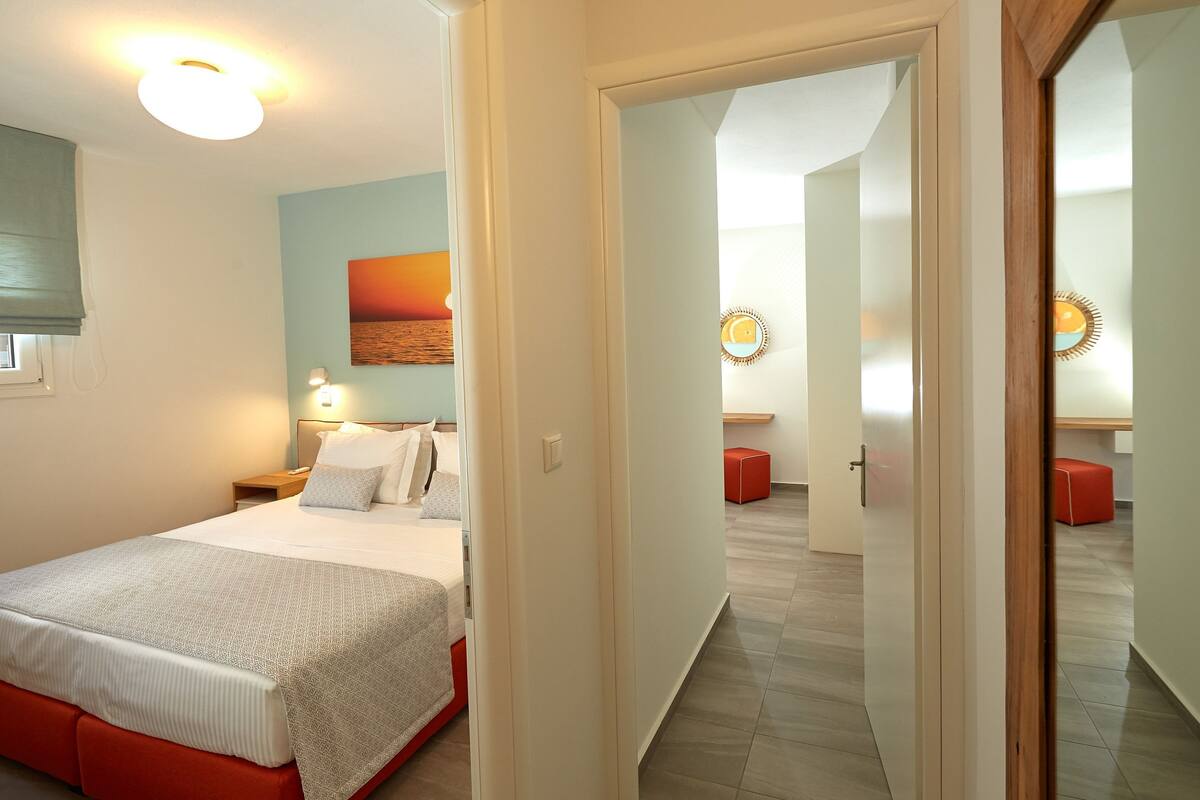 Une chambre d’hôtel avec un lit, une table de chevet, une lampe fixée au mur, un tableau et un miroir.