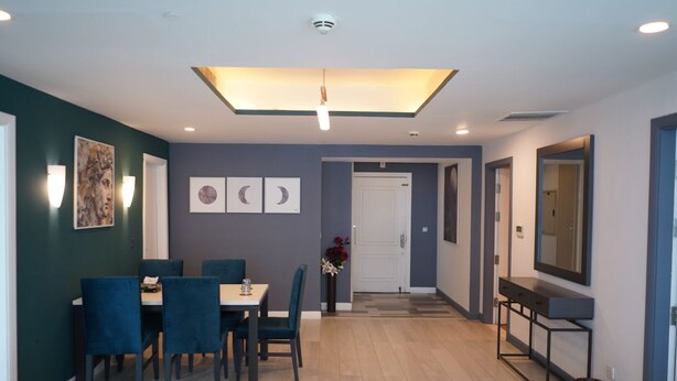 A modern interior with a dining area, a hallway, and a large mirror. - The Haven Residence (Islamabad)