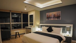 A modern hotel room with a large bed, bedside lamps, a desk, and a chair. - The Haven Residence (Islamabad)