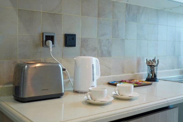 Un comptoir de cuisine avec un grille-pain, une machine à café et deux tasses posées sur des soucoupes.