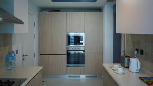A modern kitchen with wooden cabinets, stainless steel appliances, and a white countertop. - The Haven Residence (Islamabad)