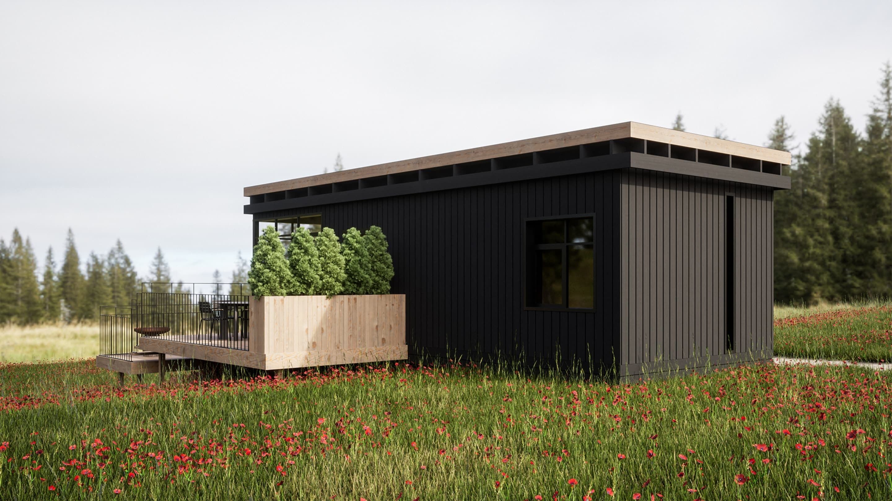 Une cabane moderne dotée d’une terrasse, entourée d’un champ de fleurs rouges.