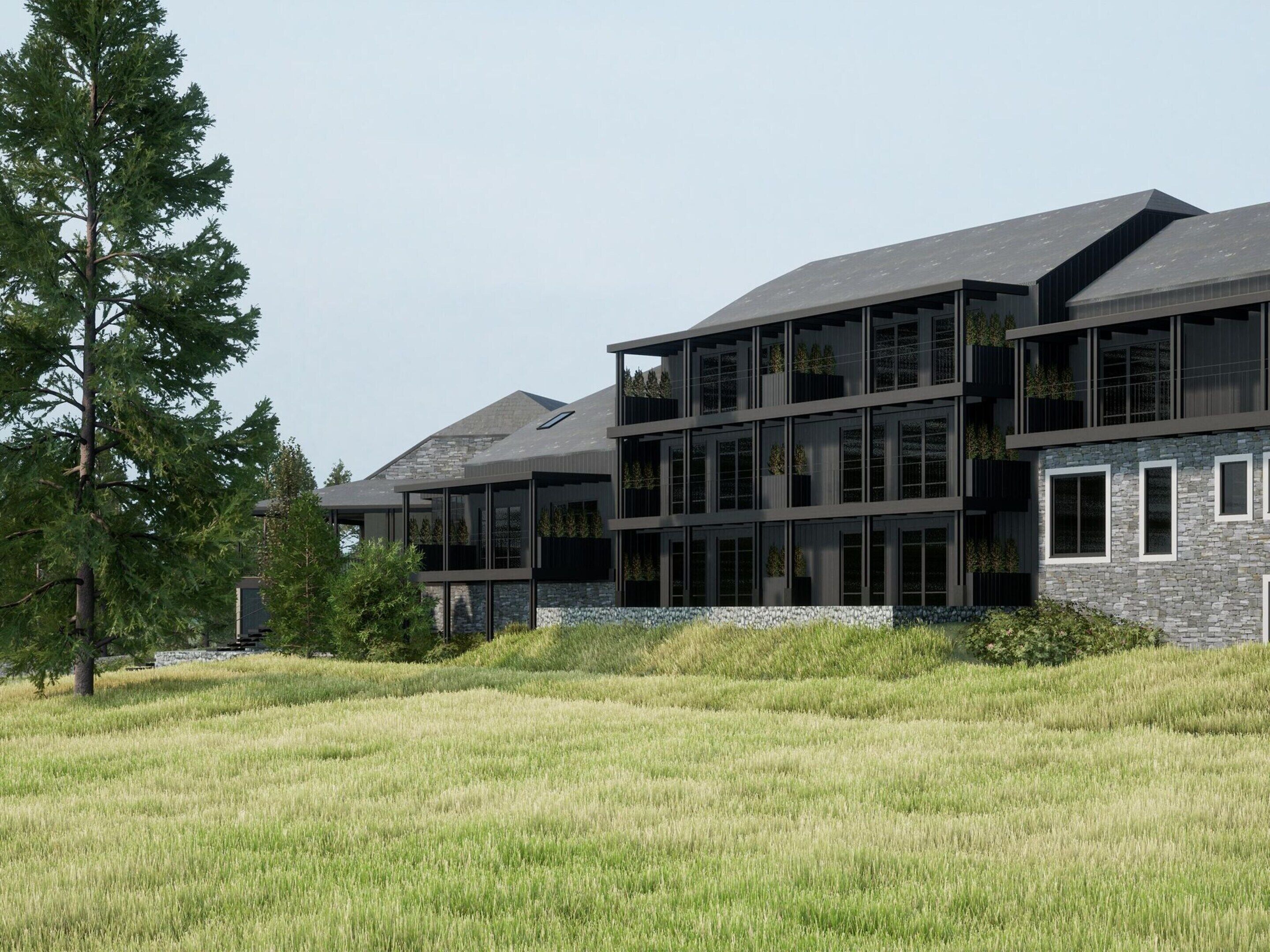 A modern multi-story building with large windows and balconies, surrounded by a grassy field and trees.