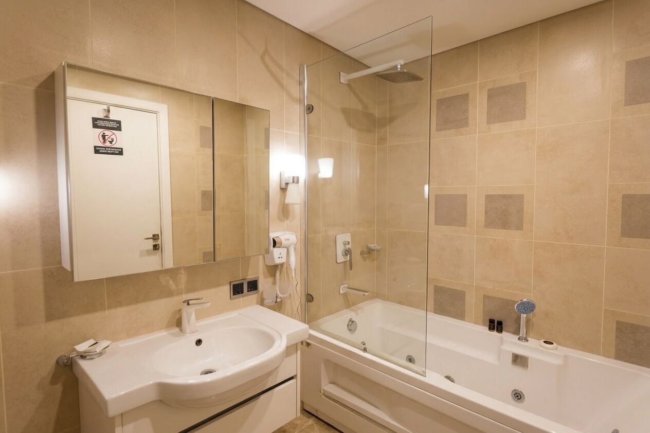 A bathroom with a sink, mirror, and shower.