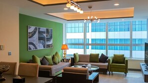 Un moderno salón con una pared de acento verde, un ventanal grande y una araña.