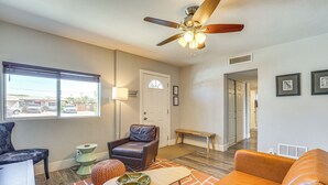 A living room with a ceiling fan, a sofa, a chair, a coffee table, and a window with blinds.
