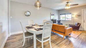 A dining area with a round table, white chairs, and a ceiling fan.