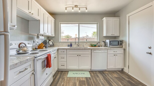 A kitchen with white cabinets, a stove, a microwave, and a window.