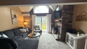 Un salon chaleureux avec un canapé, un fauteuil et une cheminée.
