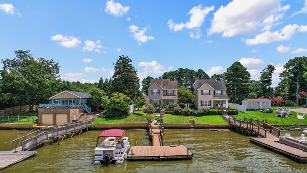 A river dock with a boat, a wooden walkway, and houses in the background. - Lakefront Paradise with Spectacular Views! (Lexington)