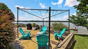 A patio with Adirondack chairs, a grill, and a view of a lake. - Lakefront Paradise with Spectacular Views! (Lexington)