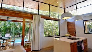 A modern kitchen with a large island, wooden ceiling, and large windows offering views of greenery. - Chic surf and yoga villa 2-minute walk to beach (Guanacaste Province)