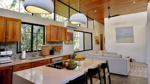 A modern kitchen with wooden cabinets, a large island, and pendant lighting. - Chic surf and yoga villa 2-minute walk to beach (Guanacaste Province)