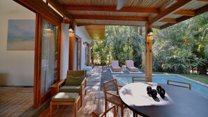 A covered outdoor area with a pool, wooden furniture, and a view of the surrounding greenery. - Chic surf and yoga villa 2-minute walk to beach (Guanacaste Province)