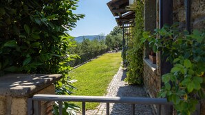 A stone pathway leading to a grassy area with a metal railing, surrounded by greenery and a stone building. - Olivetello - Three Bedroom Villa, Sleeps 7 (Trevignano Romano)