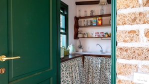 Una cocina con puerta verde, estantes de madera con utensilios de cocina y salpicadero de azulejos.