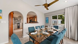 A dining area with a glass table set for six, blue upholstered chairs, and a ceiling fan. - The Villa Michelle•Luxury•Ocean Views•Heated Salt Pool•Outdoor Living (St Thomas)