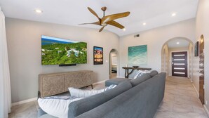 A modern living room with a large flat-screen TV, a ceiling fan, and a grey sectional sofa. - The Villa Michelle•Luxury•Ocean Views•Heated Salt Pool•Outdoor Living (St Thomas)