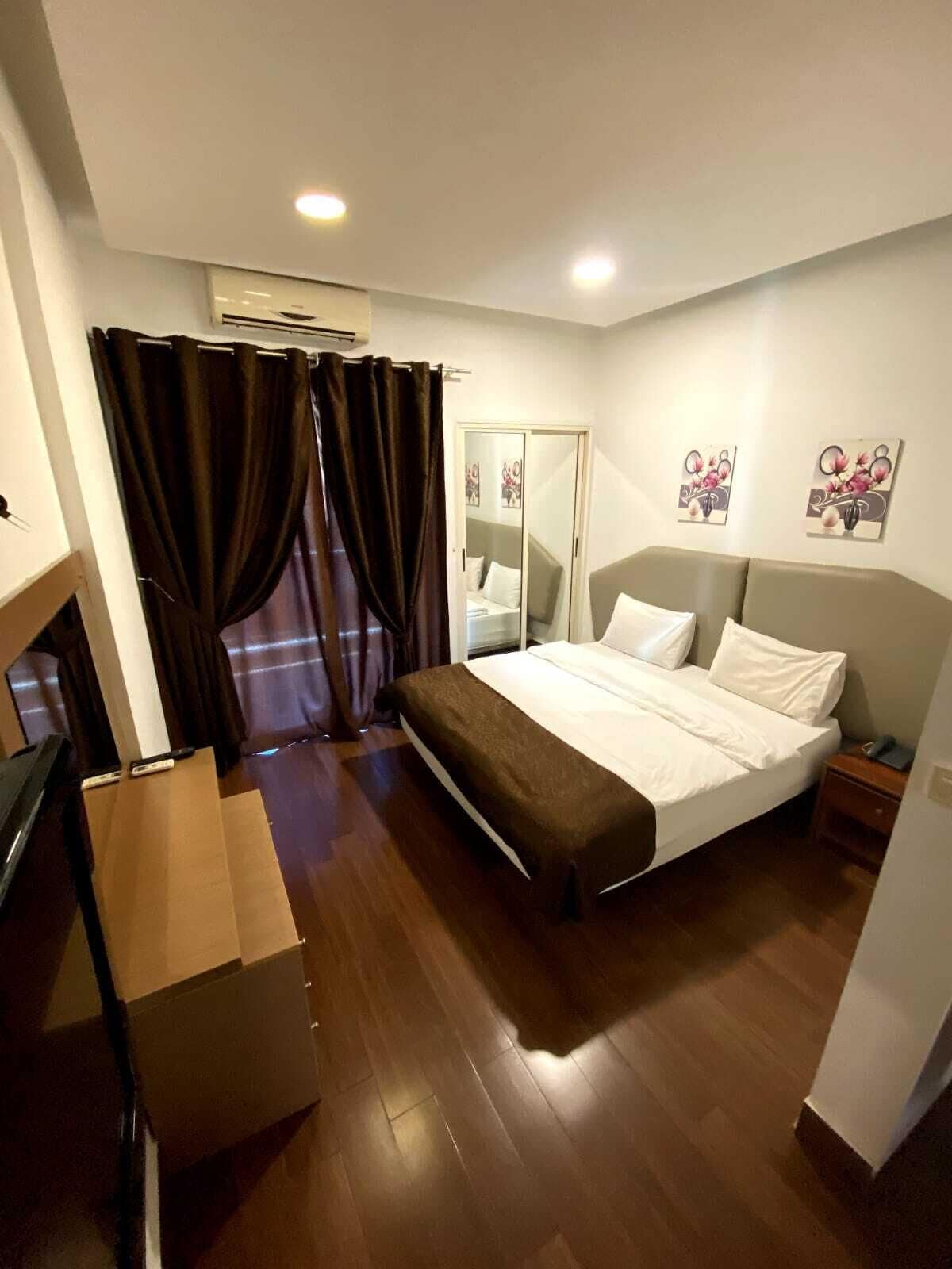 A bedroom with a bed, curtains, a wardrobe, and a painting on the wall.