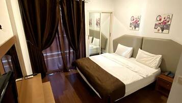 A bedroom with a bed, curtains, a wardrobe, and a painting on the wall.