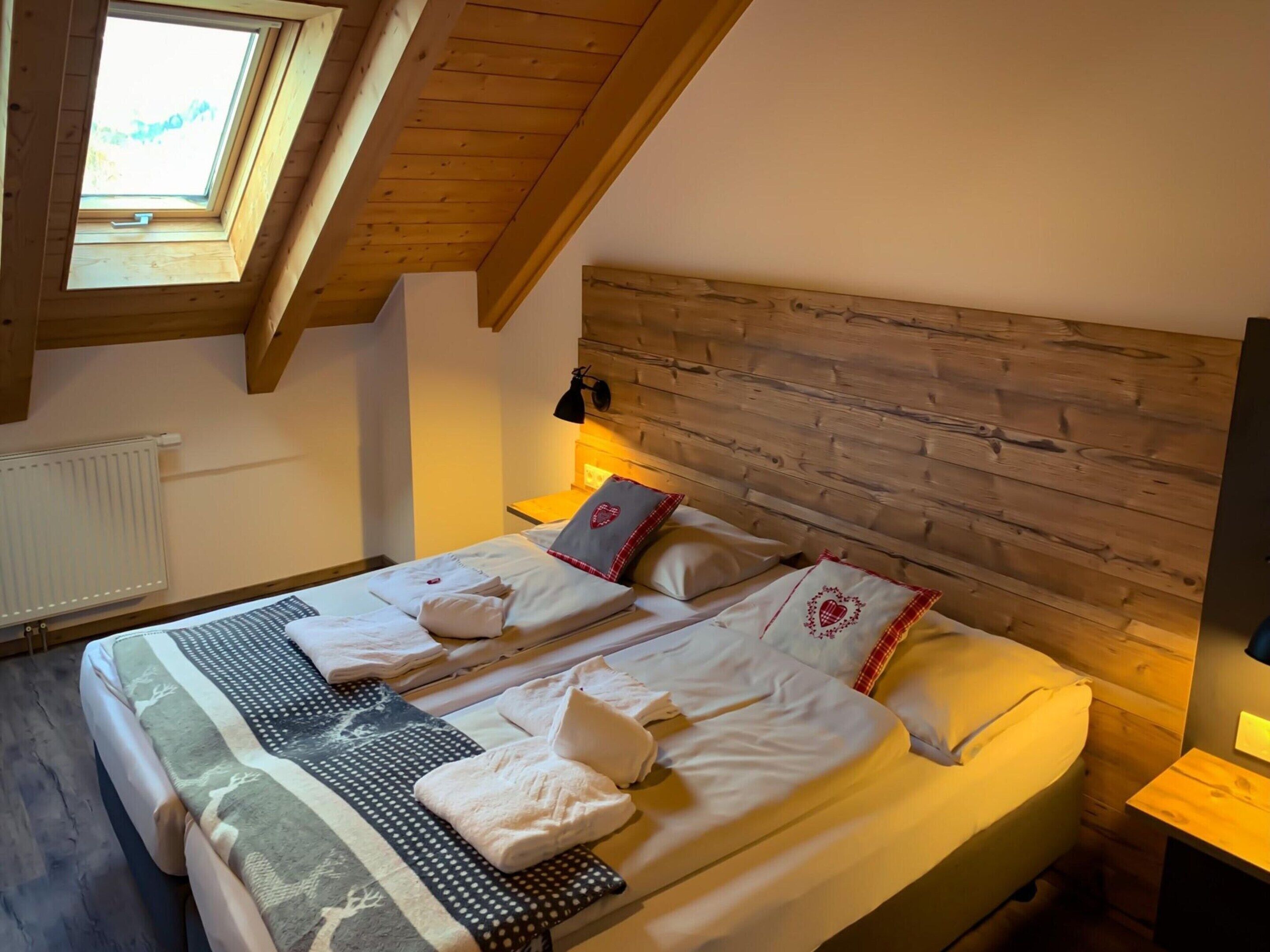 A cozy bedroom with a sloped ceiling, wooden headboard, and a skylight.