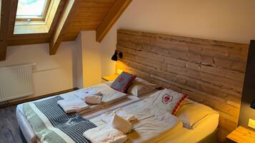 A cozy bedroom with a sloped ceiling, wooden headboard, and a skylight.