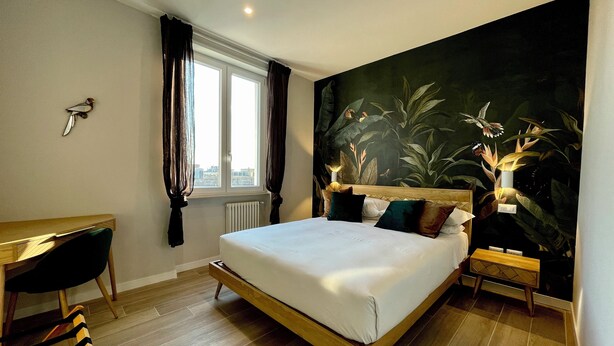 A modern bedroom with a large bed, a desk, and a city view through the window. - Your home in Rome

4 Rooms & 4 Elements 

Spacious penthouse for 12 guests
 (Roma)