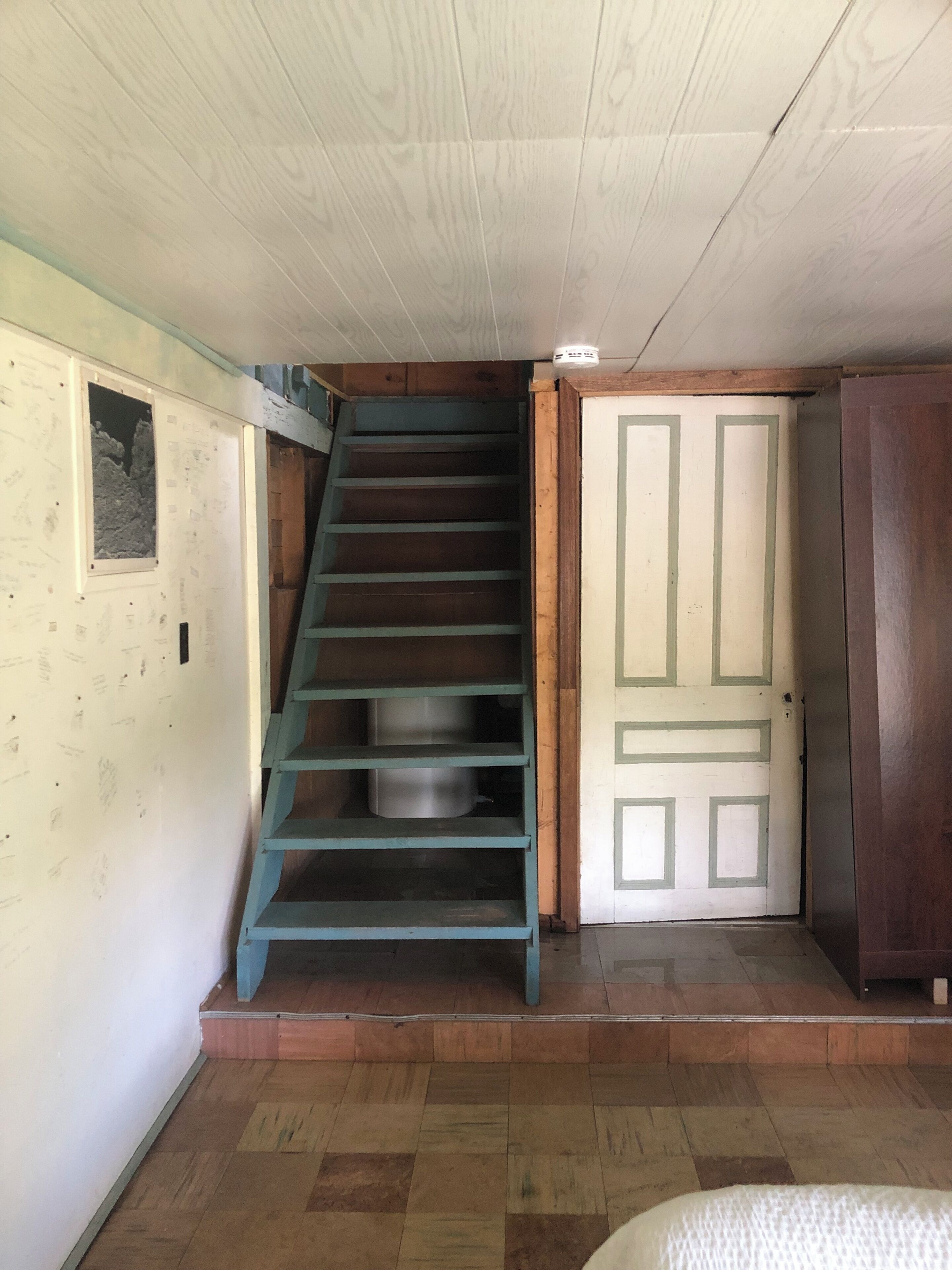 A staircase with a blue handrail leading to a door with a green frame.