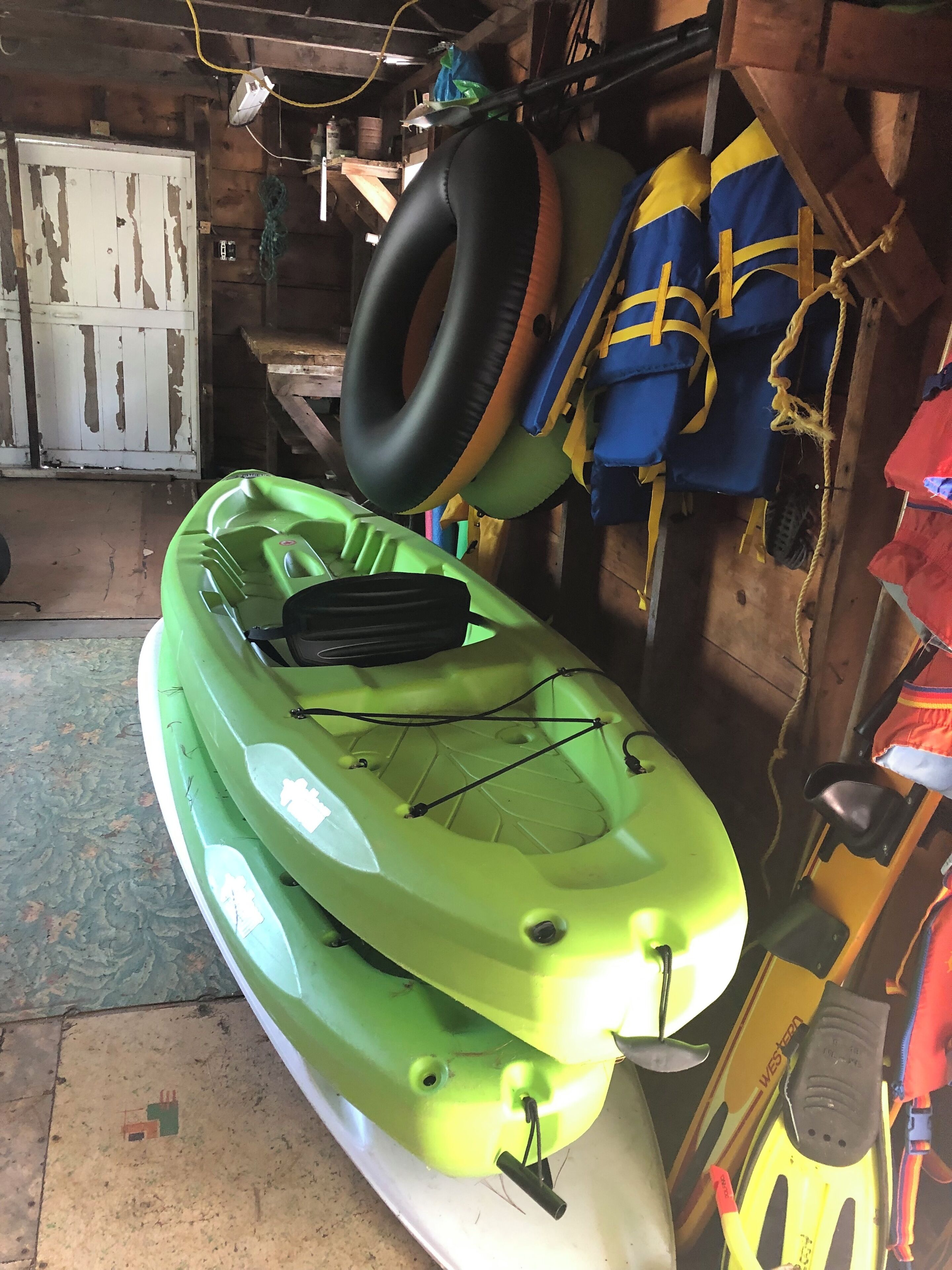 A kayak in a garage with a white door and wooden walls.