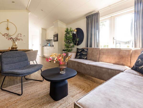 Un salon moderne avec un canapé, un fauteuil, une table basse ronde et une plante en pot.