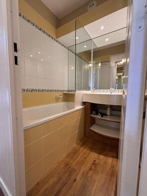 Een badkamer met een bad, een spiegel en een wastafel.