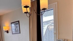 En matplats med ett träbord för fyra personer, en soffa och ett fönster med gardiner.
