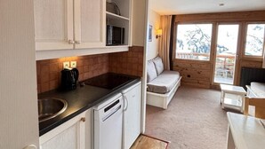 Ett kompakt kök med vita skåp, en mikrovågsugn och en kaffebryggare.