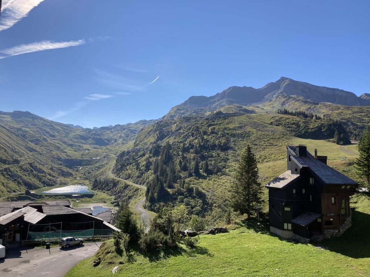 Ein Berggasthof mit großem Fenster mit Blick auf ein Tal und einen See.