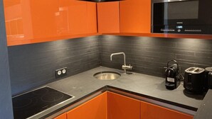 A modern kitchen with orange cabinets, a black microwave, a sink, and a coffee maker. - 10m from ski slopes, 2nd floor, view ski slopes, balcony, fireplace or stove, tv, 50m², Avoriaz (Avoriaz)