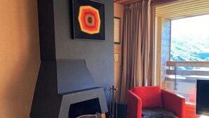 A modern living room with a fireplace, a red armchair, and a large window with a view of snow-covered mountains. - 10m from ski slopes, 2nd floor, view ski slopes, balcony, fireplace or stove, tv, 50m², Avoriaz (Avoriaz)