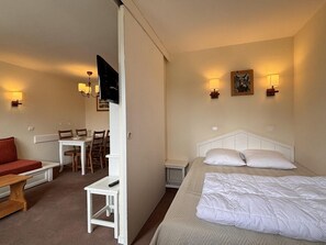 Une chambre d’hôtel comprenant un lit, un bureau, une chaise, une petite table et un téléviseur.