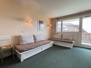 A room with a large bed, two bedside tables, a window with curtains, and a painting on the wall.