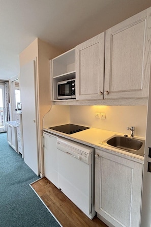 A compact kitchen with a microwave, dishwasher, and sink.