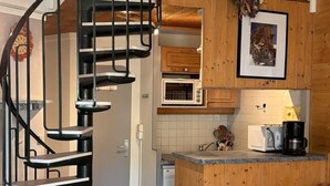 Una cocina compacta equipada con microondas, cafetera y un lavamanos pequeño.
