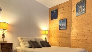 Un dormitorio con una cama, dos mesitas de noche y paredes de madera.