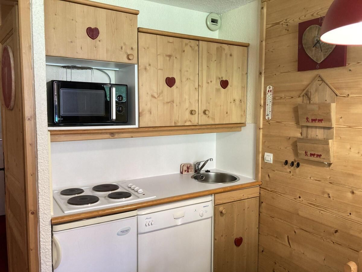 Une cuisine de taille réduite, dotée de meubles en bois, d’un four à micro-ondes, d’une cuisinière et d’un lave-vaisselle.