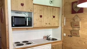A compact kitchen with wooden cabinets, a microwave, a stove, and a dishwasher.